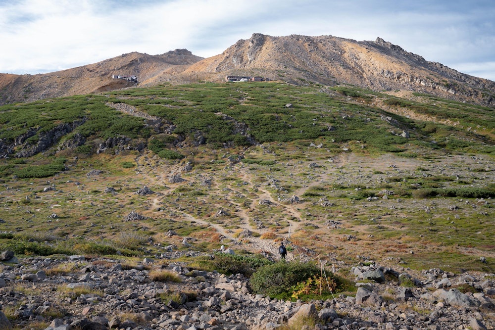 <p>さらに歩き進めると、何やら広大な平地に出た。<br>賽の河原だ。ここが標高 3000m の山の上にあるとは思えない、不思議な場所。</p>