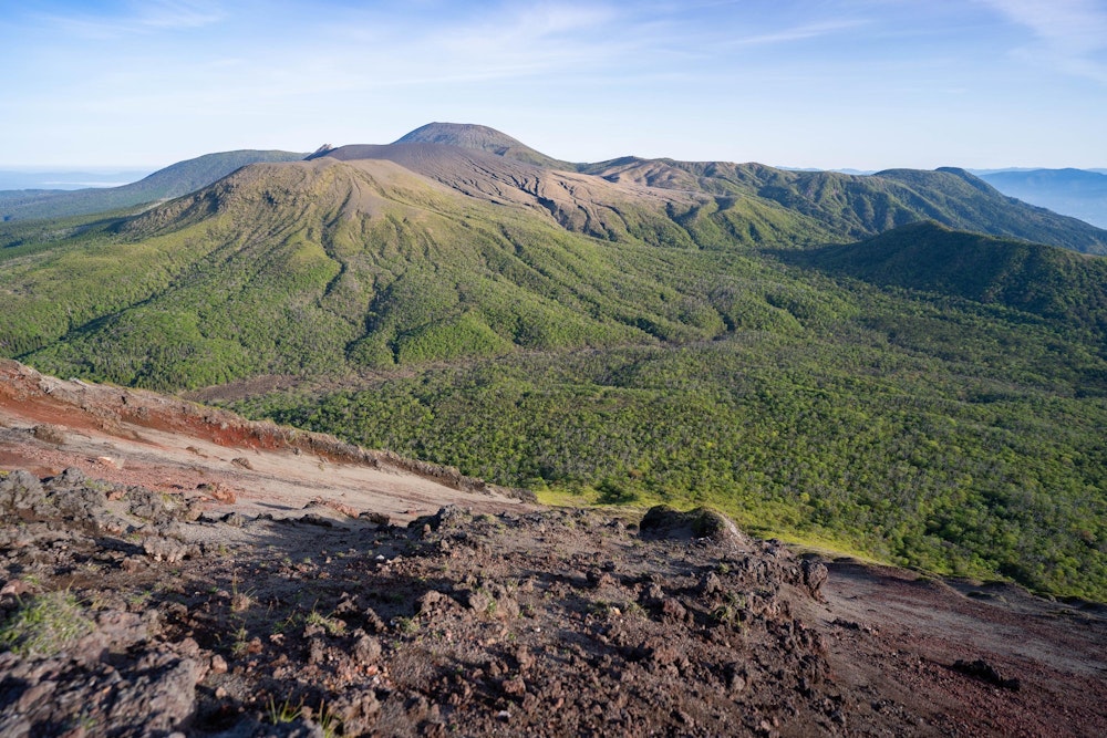<p>韓国岳方面を望む。<br>見てのとおり、間に道はない。<br>このまま斜面を駆け降りて、手前に見える森を突き進む。</p>