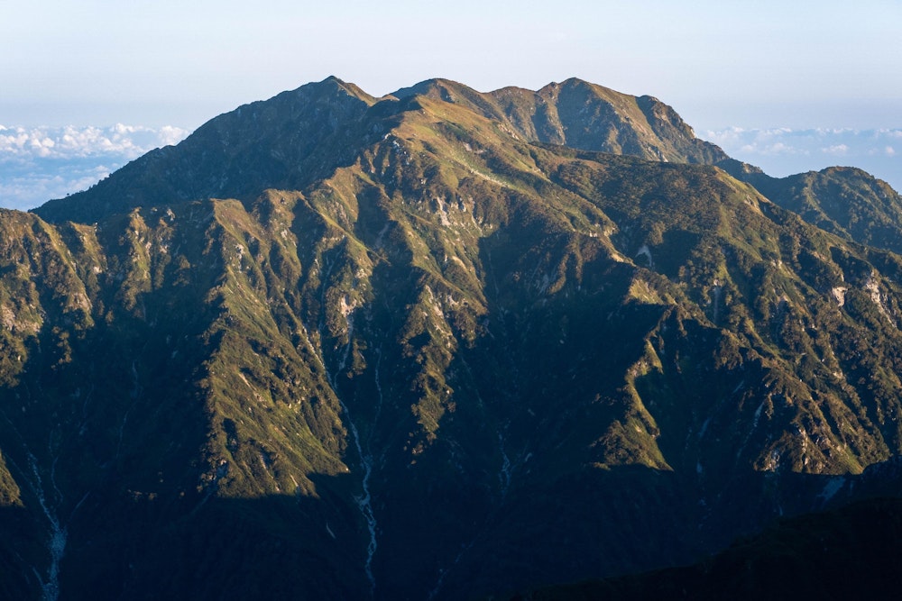 <p><span style="color:#000000">朝の日差しを浴びて輝く毛勝山。</span><br><span style="color:#000000">思っていたよりずいぶん立派な山だ。</span></p>