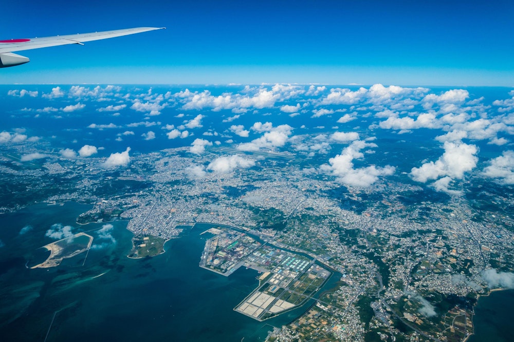 <p>飛行機で沖縄本島へ。上空から見るうるま市街地。<br>夏らしいちぎれ雲が、低い空に浮かんでいる。</p>