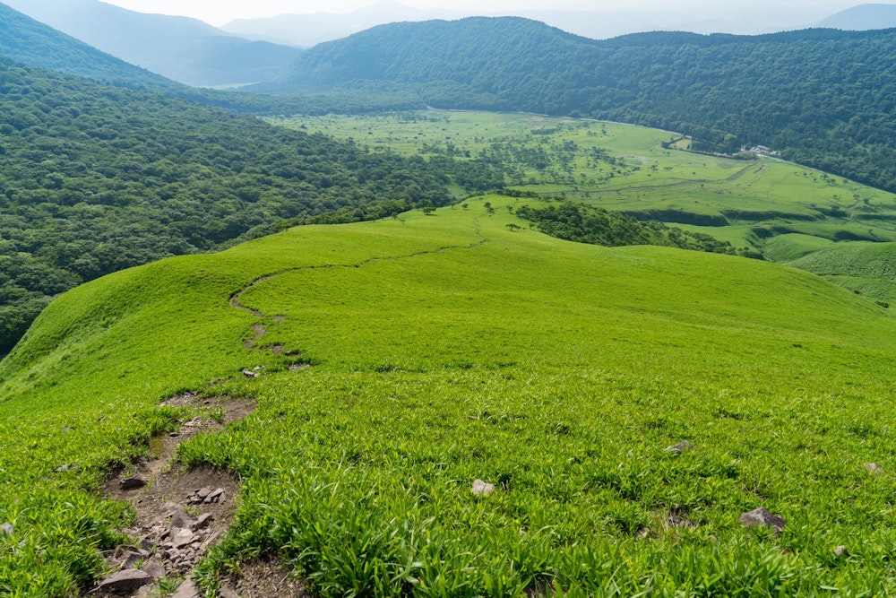 <p>飯盛ヶ城から正面登山口に向けての道のりも気分爽快そのもの。<br>草原の上に敷かれた一本道を、登山口まですべて目で辿ることができる。</p>