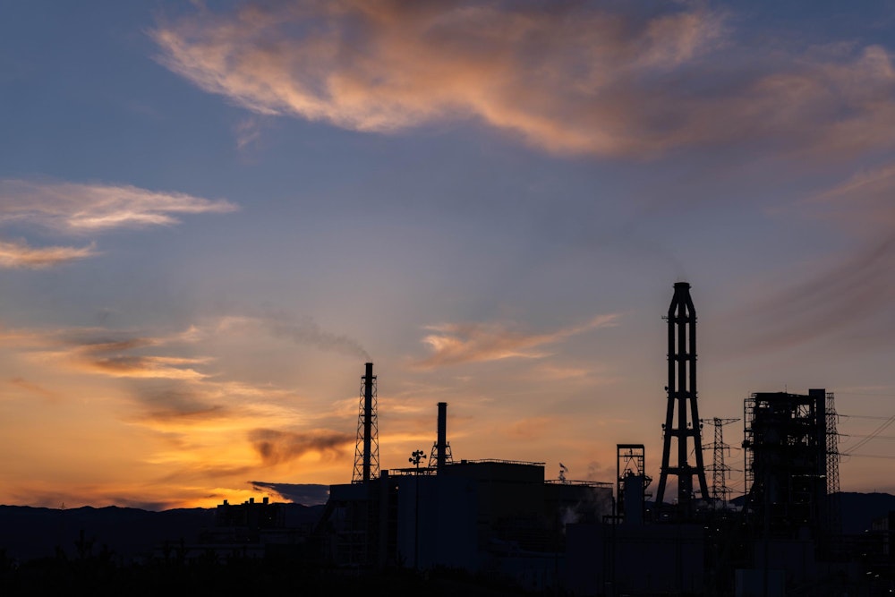 <p>火力発電所の煙突群のシルエットが夕空に浮かび上がる。</p>