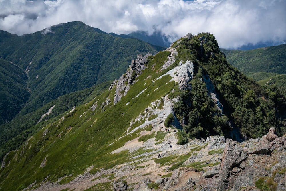 <p>塩見小屋方面に下っていく。<br>塩見岳頂上直下は急峻な岩場になっており、冬季は難しそうだ。</p>
