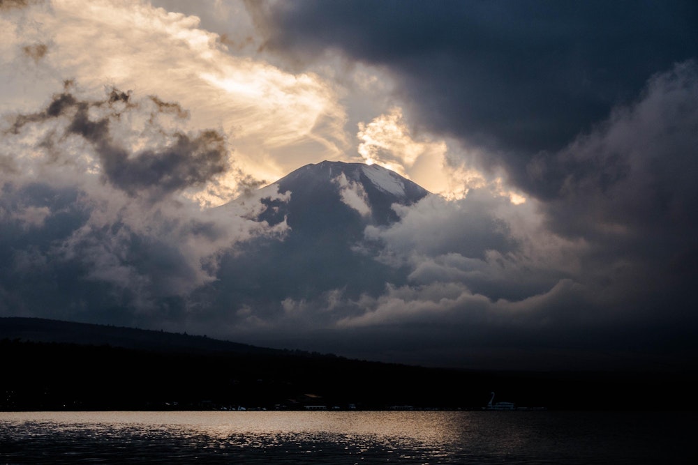 <p>雲間から顔を出す夕刻の富士山。<br>雲が多い天気であったが、それが逆に富士山に神秘的な雰囲気を纏わせていた。</p>