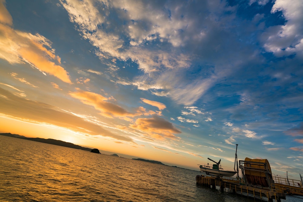 <p>沈む夕日。<br>低い雲が先に色づくが、高い雲はまだ白い。ここから上の雲も色づいていくだろう。<br>この時点で最高の夕焼けショーが始まることが明らかだった。</p>