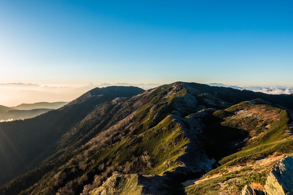<p>朝日に浮かぶ縦走路。太陽が低いうちは、山の陰影がはっきりと浮かび上がり、ダイナミックな風景を楽しめる。</p>