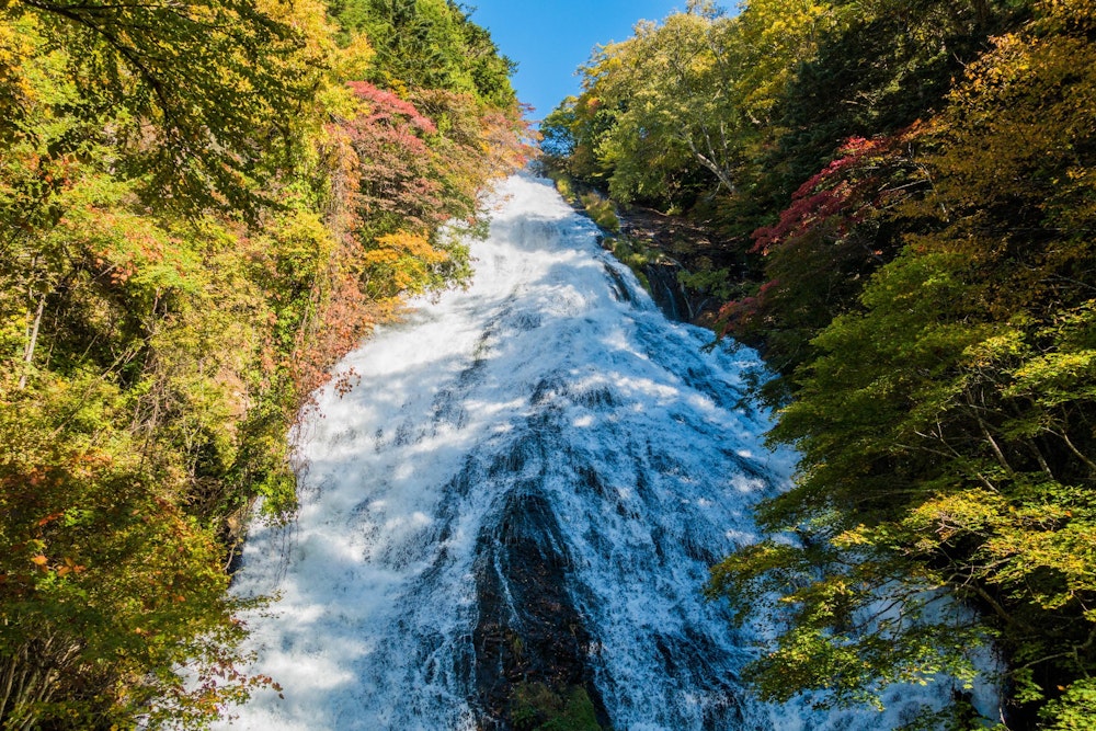 <p>湯滝。緩やかな傾斜状になった大きな岩壁を、湯川の水が薄く広がりながら流れ落ちる。</p>