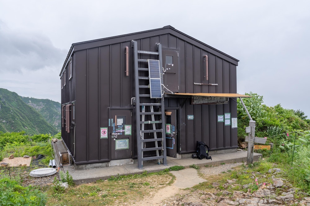<p>三国岳避難小屋。<br>川入登山口からのルートだと山頂までに 3 つの小屋を通ることになるが、ここがその 1 つ目。<br>いずれの小屋も営業が行われるのは 7 月に入ってからになるため、この時期は避難小屋として無人解放されている。</p>