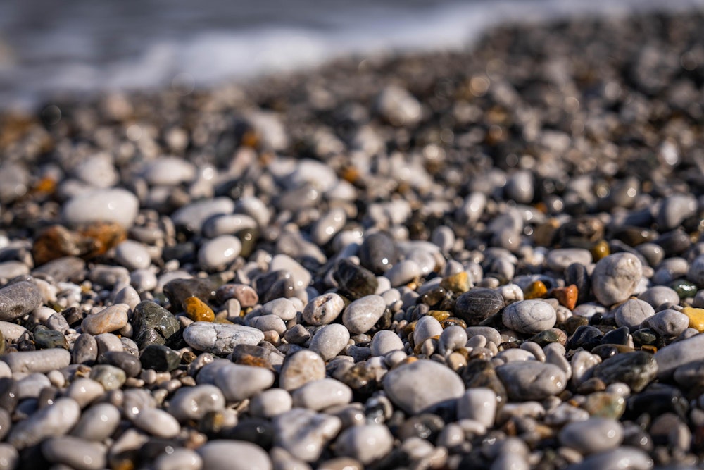 <p>何度も何度も覆いかぶさる波によって、丸く削られて鉱石のように輝く海岸の砂利。</p>