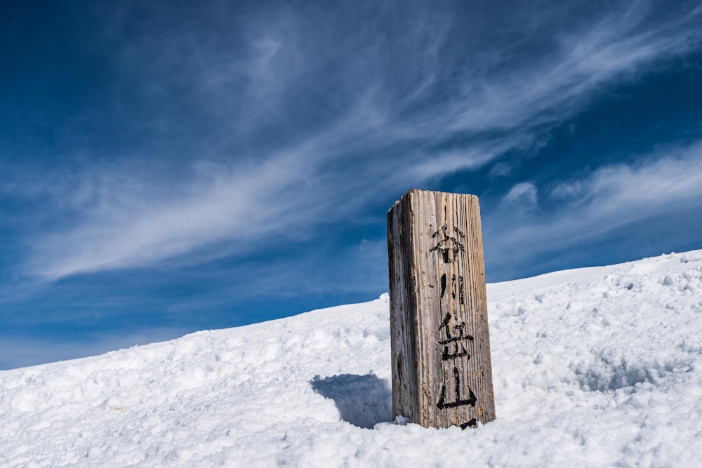 <p>雪に埋まる山頂標識。</p>