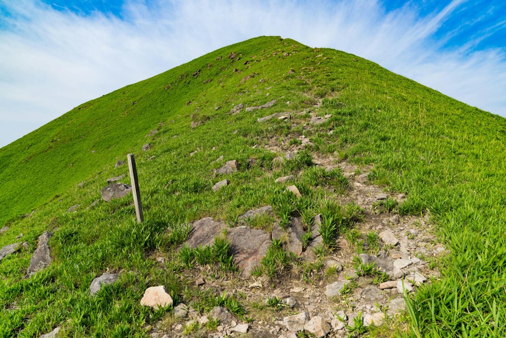 <p>正面登山口にまっすぐは帰らず、その横にある飯盛ヶ城に寄り道する。<br>全体が草原に覆われた小高い丘のような感じで、上からこれが見えたとき、寄らない手はないと思っていた。<br>空に広がる雲が集中線のようになって「ジャーン！」みたいな感じになっている。</p>