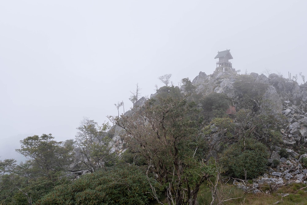<p>霧に包まれてしまったが、国見岳の山頂の祠が見えた。</p>