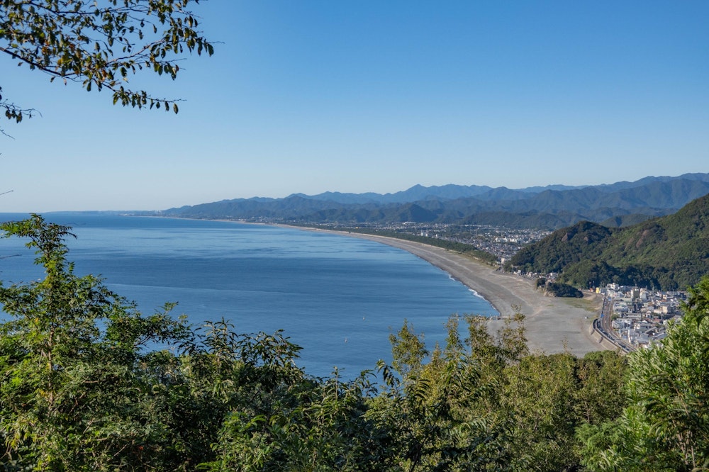 <p>再び山道に入り、松本峠まで登ると、今度は圧倒的スケールの海岸線が目の前に広がる。<br>七里御浜と呼ばれる、日本一長い砂礫海岸で、目の前の熊野市中心部のある地域から、はるか遠く新宮方面まで続いている。</p>