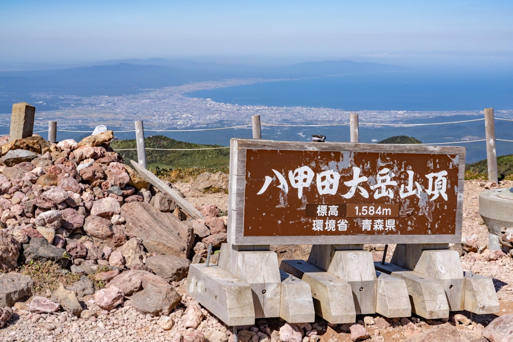 <p>頂上部はとんでもない爆風が吹きすさいでいた。<br>遠景は青森市街地。<br>2020 年の年初に訪れた真っ白な八甲田山から 5 年ぶり 2 回目の登頂。</p>