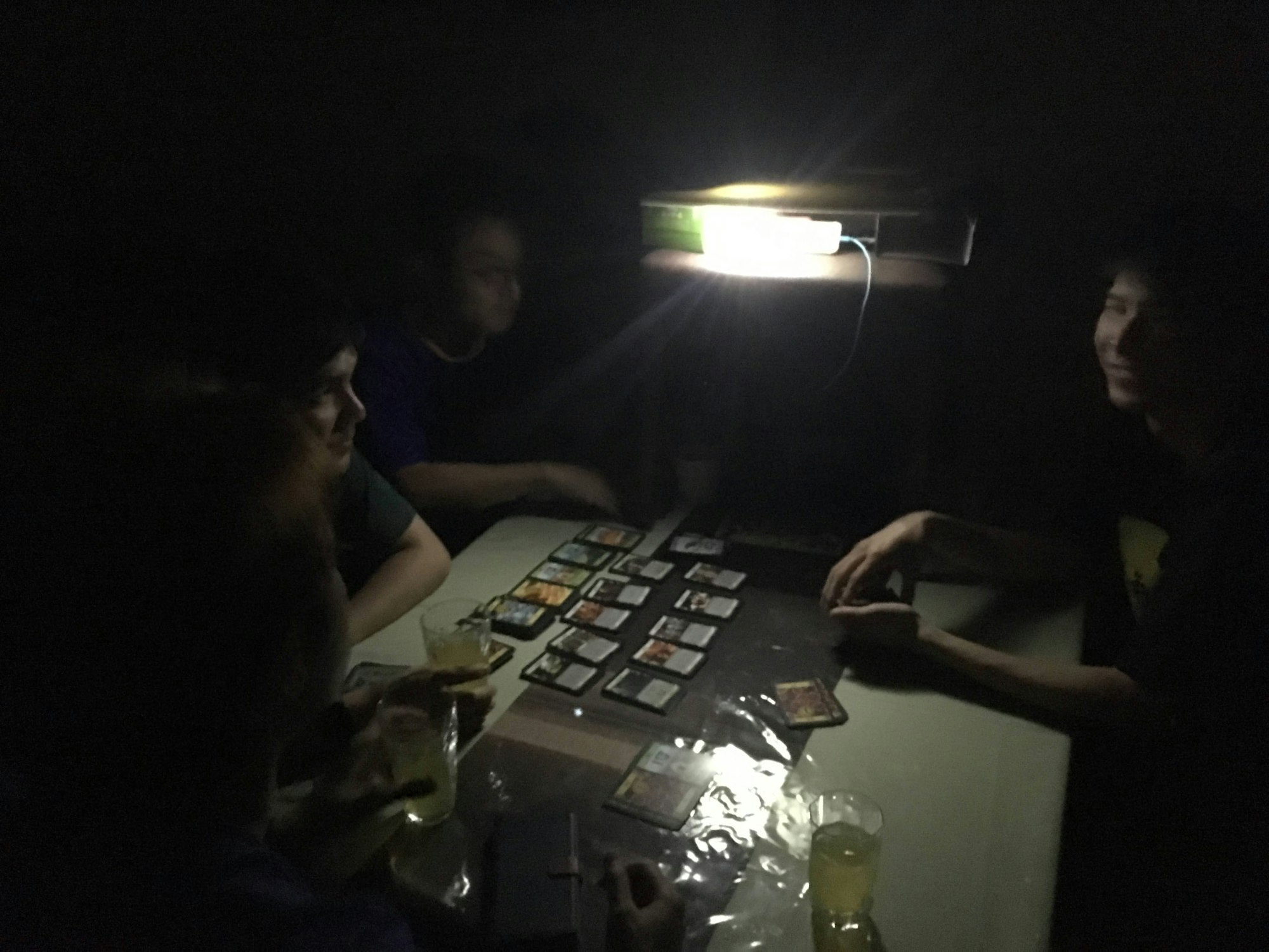 停電中、スマートフォンの灯りのみでボードゲームをする様子