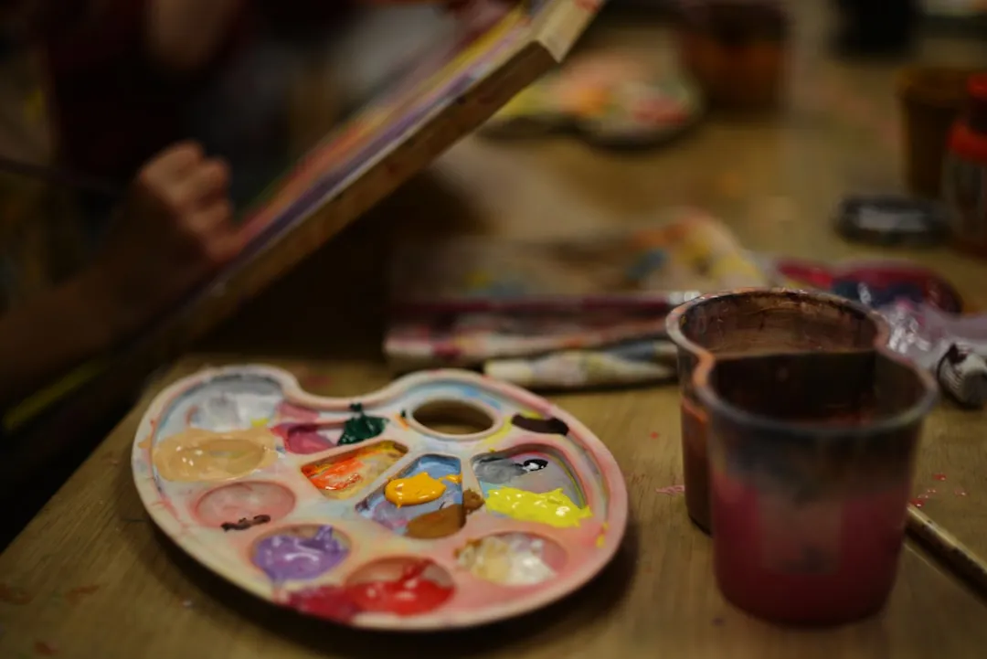 絵筆や絵の具などの創作ツールが並ぶ机:子ども向け施策で活用される体験型・知育コンテンツのイメージ