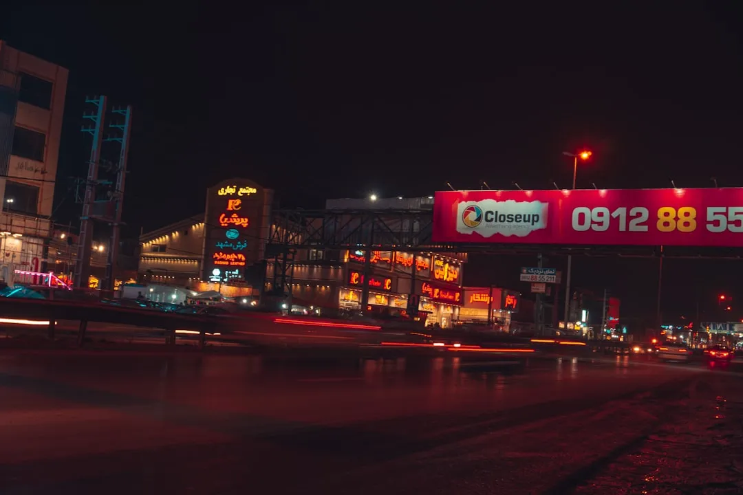 夜の都市ビルに囲まれた屋外広告サイネージのイメージ。OOHは物理的に回避が難しい点が特徴