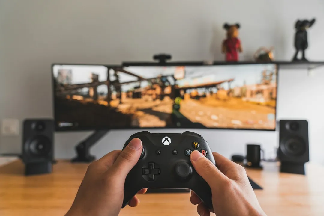 ゲーム用コントローラーを両手で持ち、モニターに映るゲーム画面をプレイしている様子