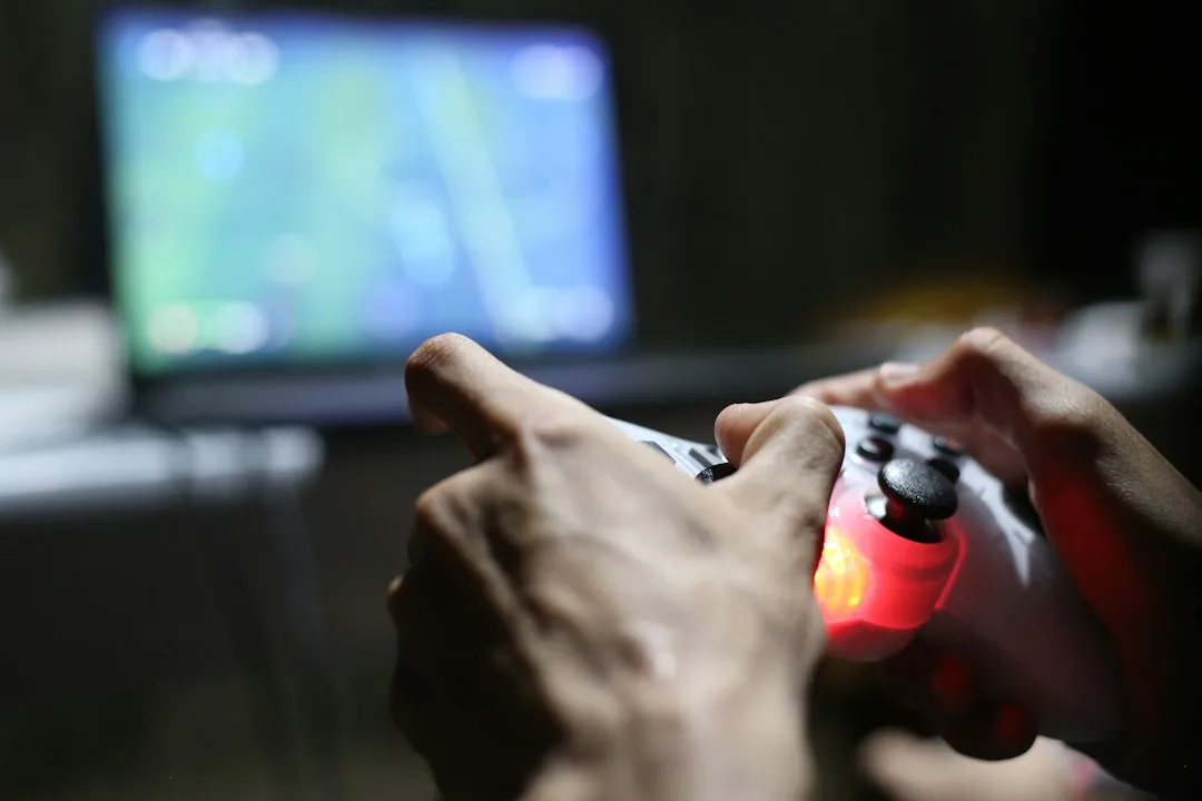 テレビ画面の前でゲームのコントローラーを操作する手元