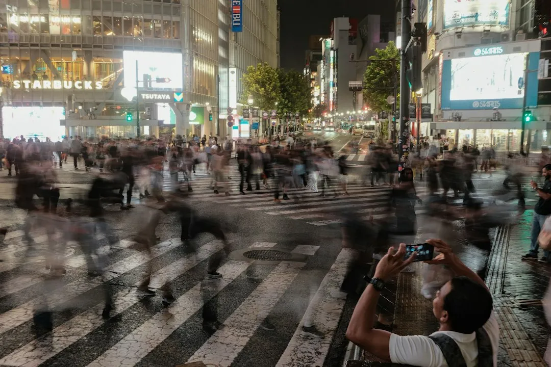 夜の渋谷スクランブル交差点でスマートフォンを構える人のイメージ