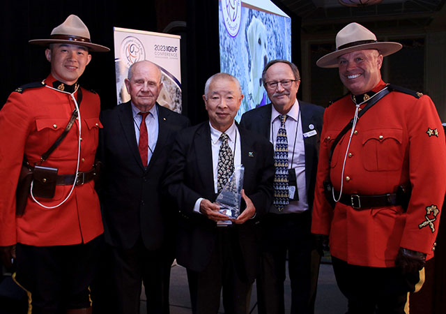 Sam Tawada (centre) shares his joy with William Thornton (second from right), Chair of the International Guide Dog Federation, John Gosling (fourth from right) and two ‘Mounties’ or Royal Canadian Mounted Police officers on each end at the awards ceremony.