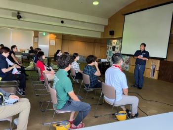 More than 20 JGDA staff sitting in a room with a screen in the front is receiving advice from a local fire fighter.