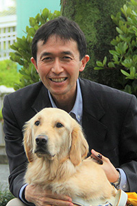Yoshiyuki in a suit, with a golden retriever in a harness.