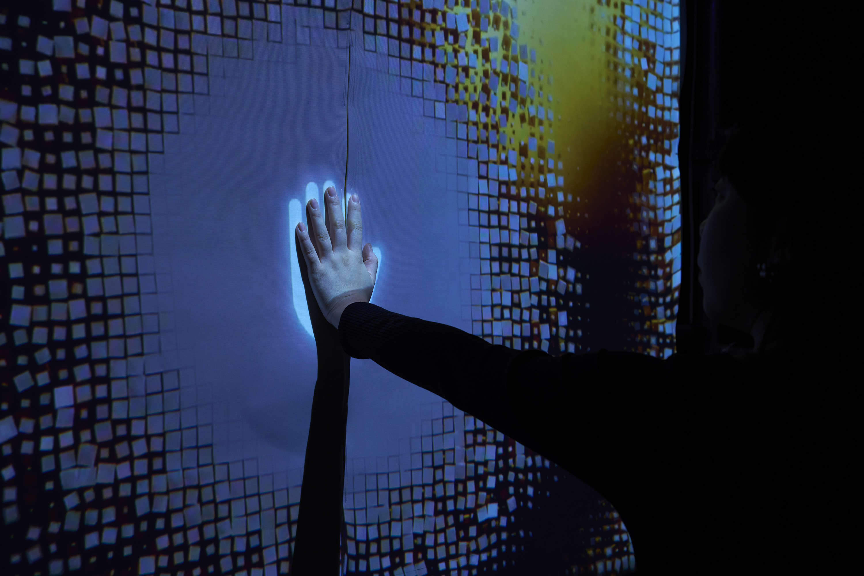 Ambience Wallを体験中の人が壁に手を当てている様子を撮影した画像