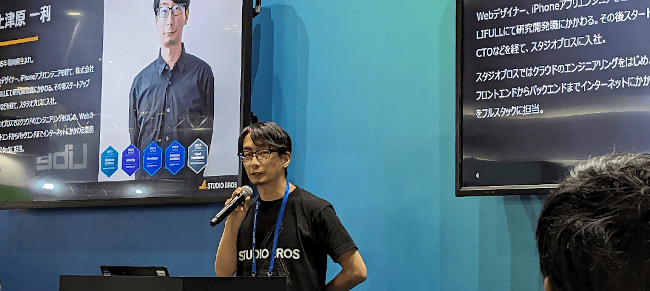 セミナーで弊社社員が登壇している。モニターにプロフィールが投影されている場面。