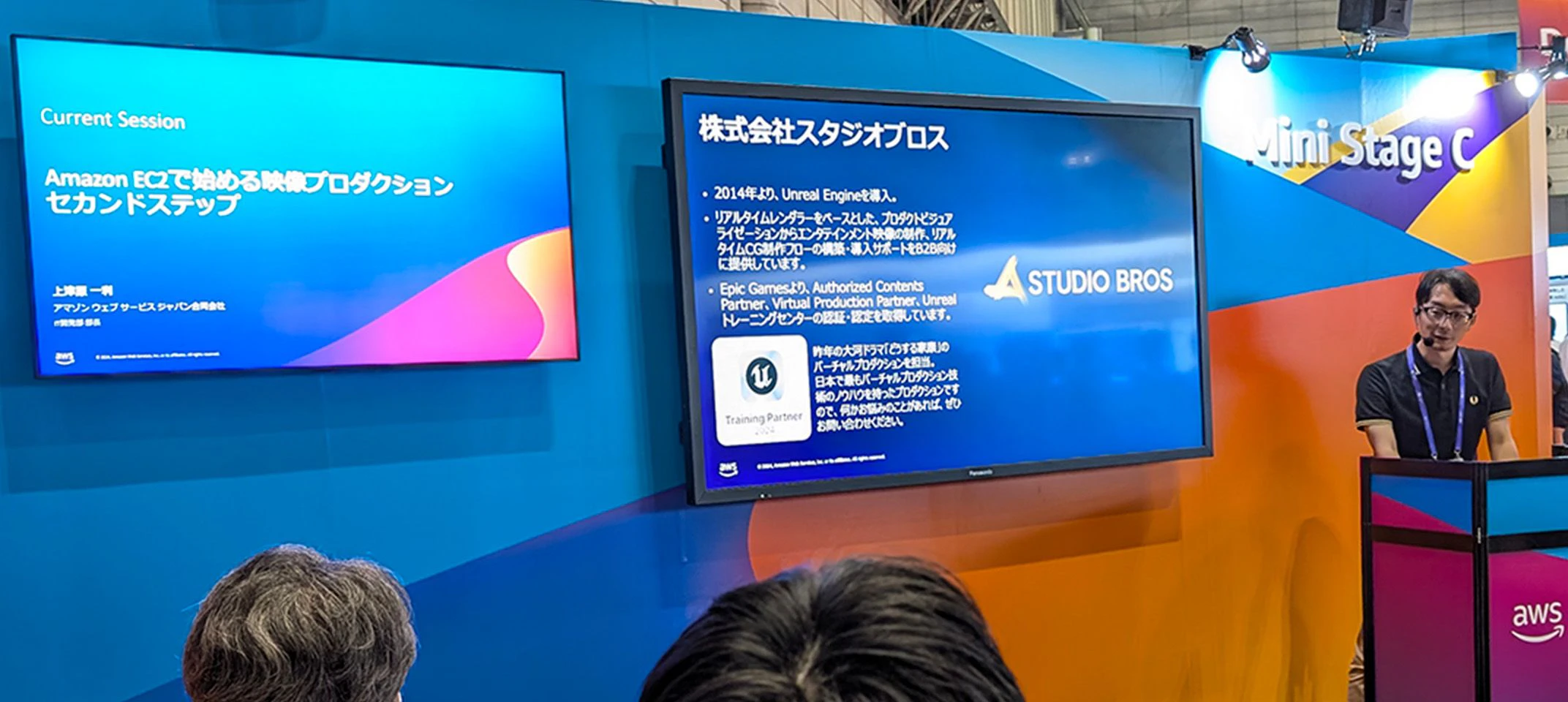 ミニステージで登壇している様子。モニターに弊社社員のプロフィールが投影されている場面。