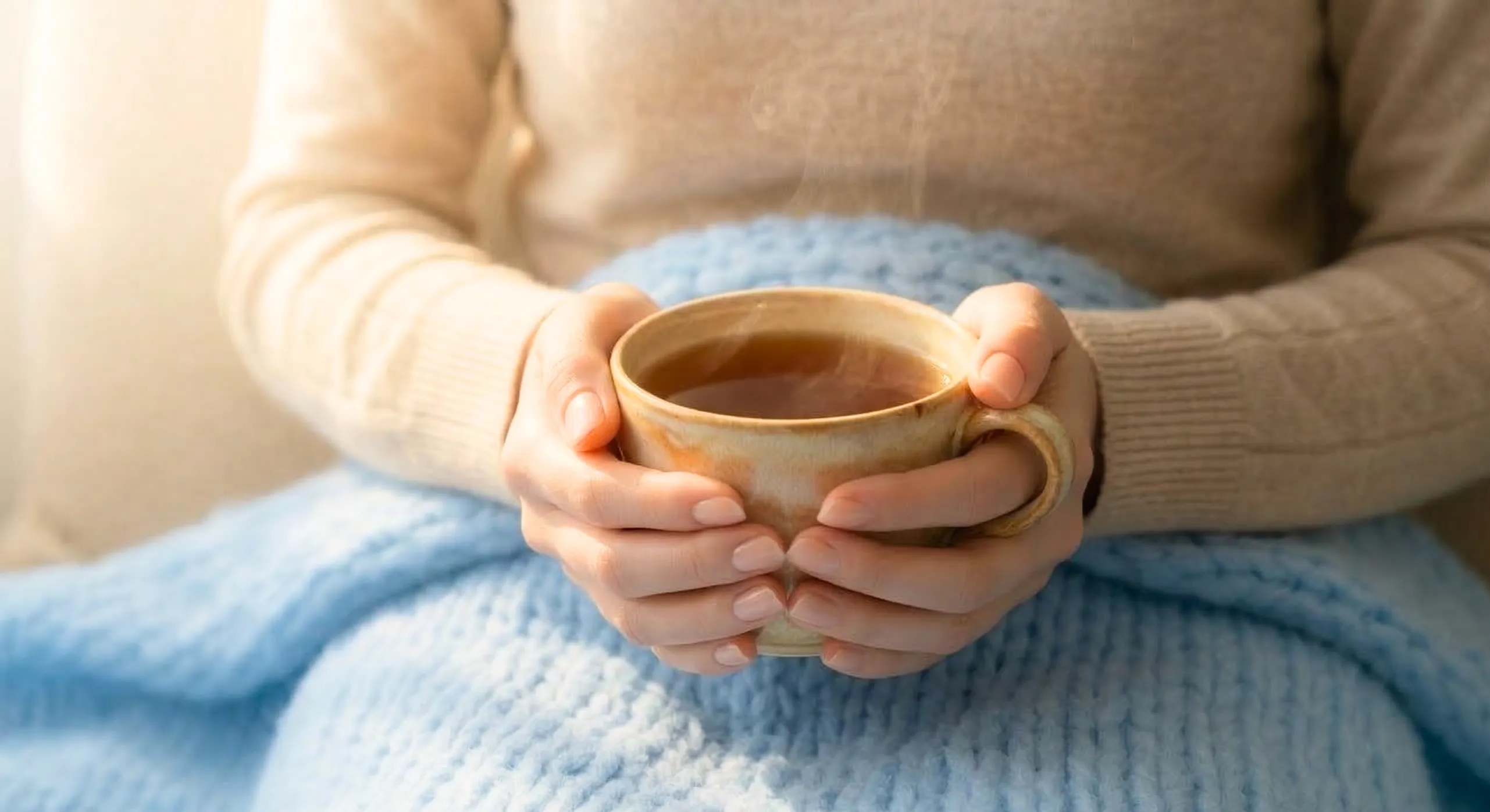 ホットドリンクを両手で抱えている