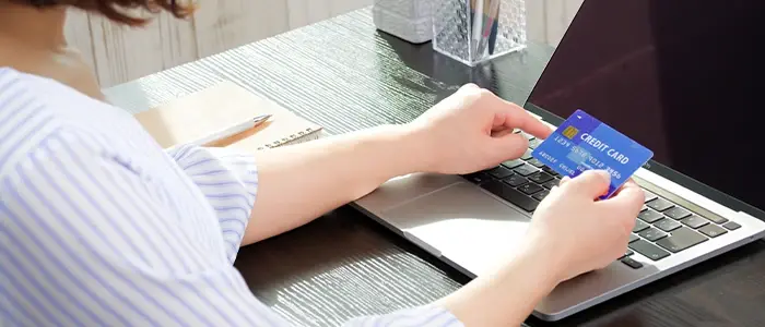パソコンの前でクレジットカードを確認する女性