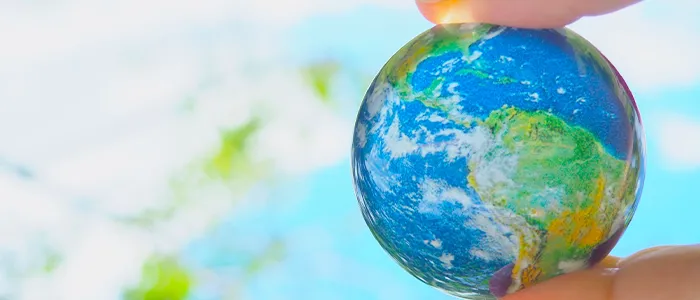 手で空にかざした地球の模型