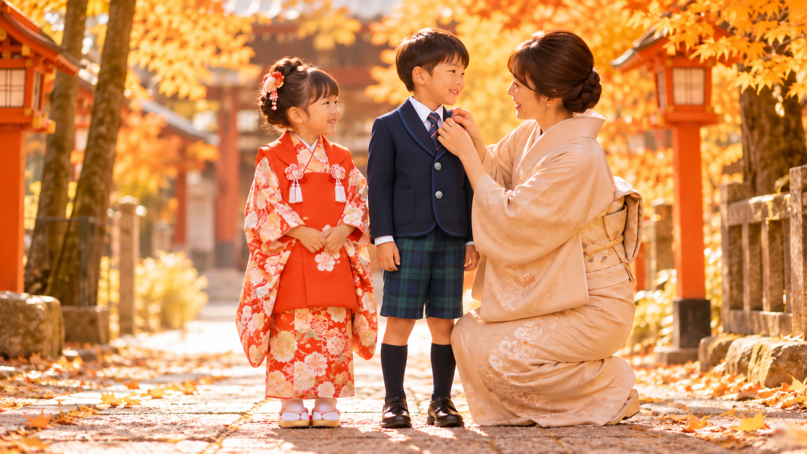 秋の神社の参道で、被布を着た3歳の女の子と園の冬の制服を着た5歳の男の子が並び、母親が男の子の襟元を整える様子