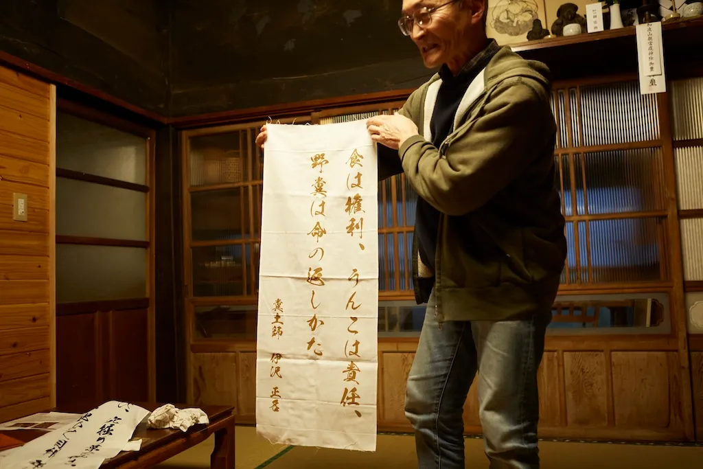 Large hand towel with Mr. Izawa's philosophy written on it. Written in brush strokes, it reads, "Food is a right, feces is a responsibility, and feces is a way of giving back life.