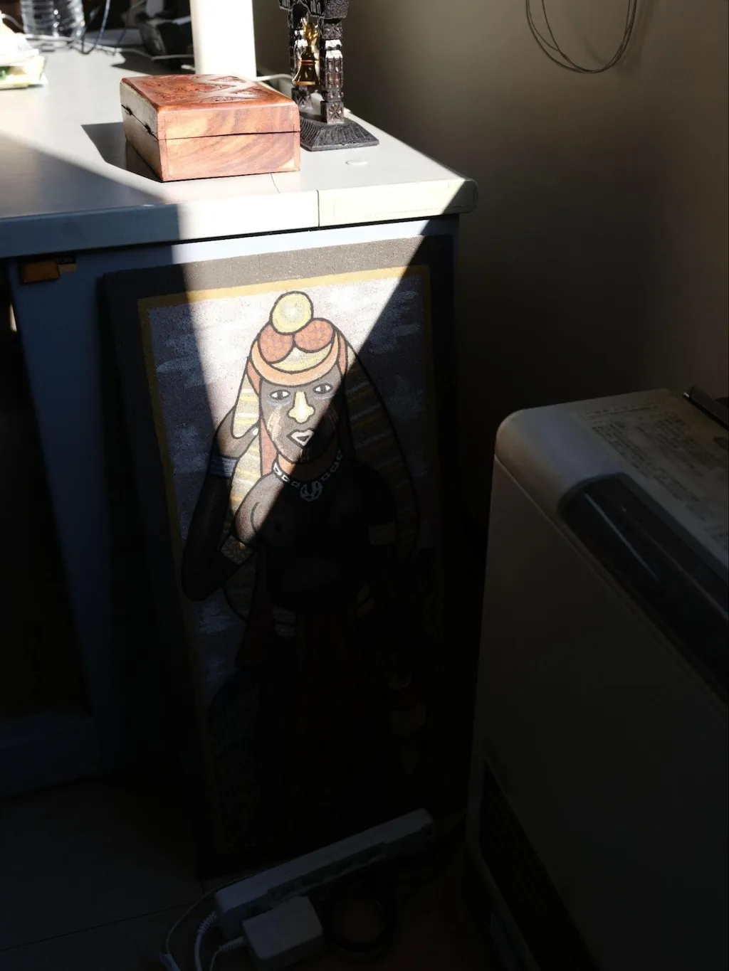 Photo of sundry items and a painting in the lab from an ethnic group in Papua New Guinea. A portion of the painting is obscured by shadows due to light shining in through the window.