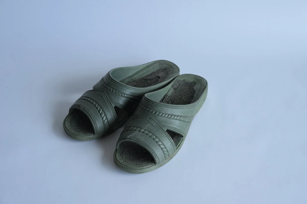 Deep green lavatory sandals, matching left and right. Faint stains throughout.