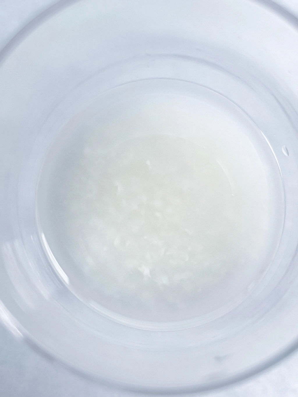 透明なコップの中に入った甘酒をクローズアップで捉えた作品。背景も白いので輪郭が分かりづらく、境界が溶けているようにも見える。