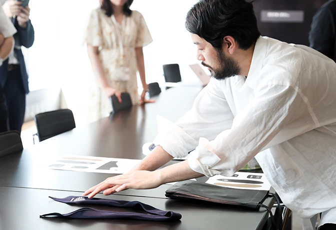 A photo of Nakata going over uniform samples placed on a desk.