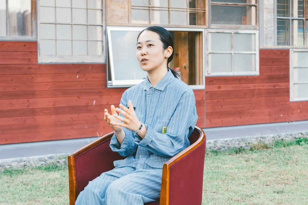 Photo of Ms. Otsuka. She is sitting in a chair talking.