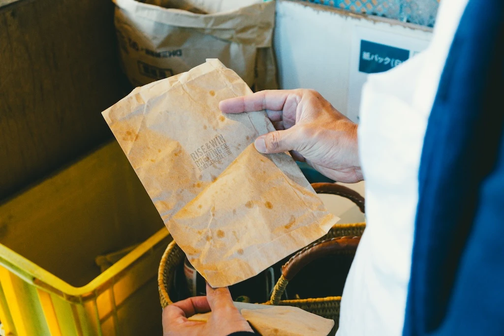 A photograph of a hand holding a brown piece of paper with grease stains on it.