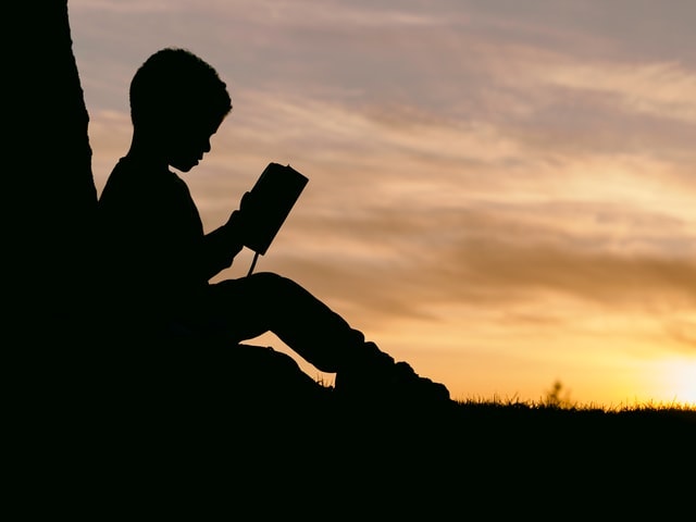 夕焼けと本を読む少年