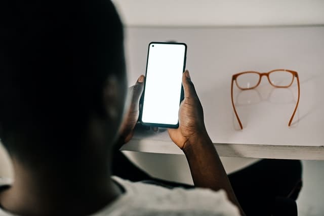 メガネを外してスマートフォンを操作する男性