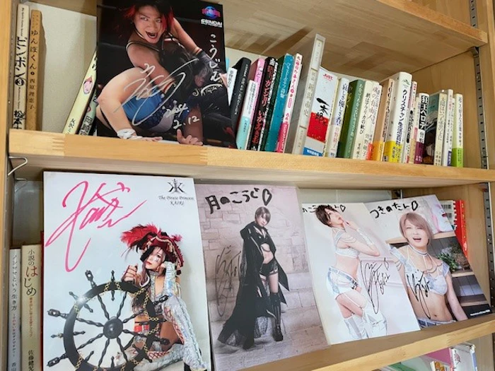 「生きられる依存」に切り替えた月乃光司さんの本棚には、安納サオリさん（右下）らファンになった女子プロレス選手のサインが並ぶ＝2024年2月17日