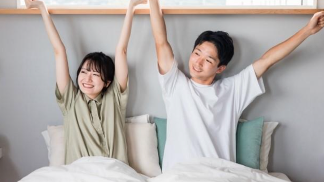 寝室で腕を伸ばす仲の良い夫婦