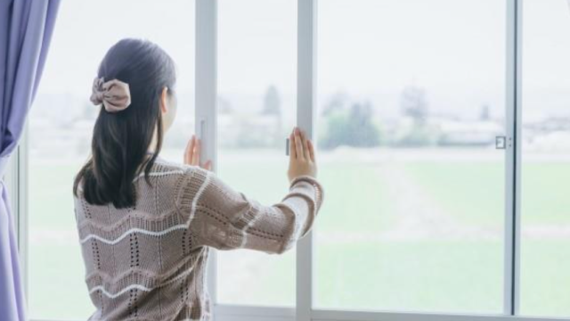 窓を閉めようとしている女性