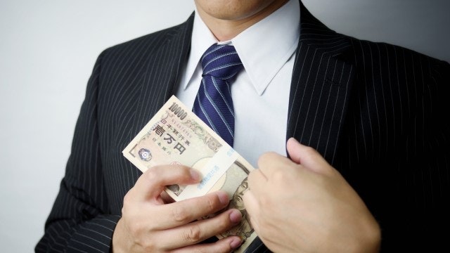 スーツの男性が懐にお金を入れようとしている様子