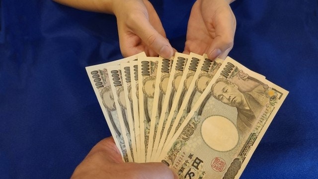 男性が女性に現金を渡している様子