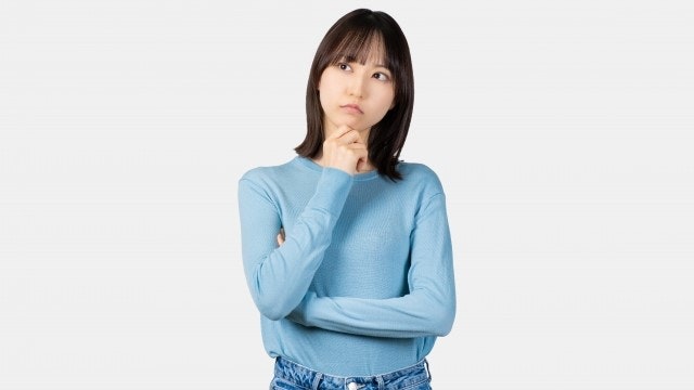 顎に手を添えて考えている女性の様子