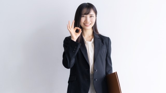 OKマークをするスーツの女性